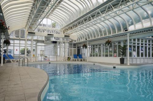 a large swimming pool with a glass ceiling at Basingstoke Hotel in Hook