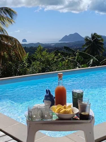 a table with a bowl of chips and a bottle of juice at Villa CosaRoé-Vue Mer-Piscine-3 étoiles in Rivière-Salée