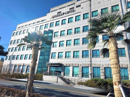 a large building with palm trees in front of it at Ocean Hotel Pohang in Pohang