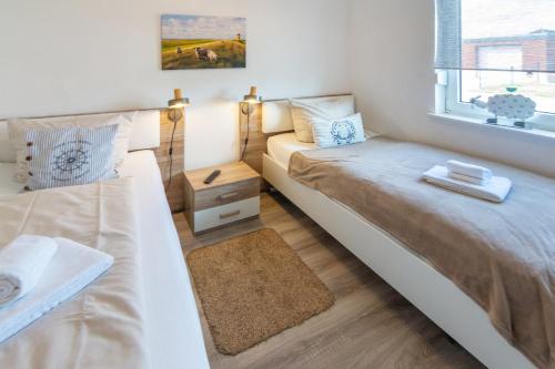 a small bedroom with two beds and a window at Deichgraf in Dornumersiel