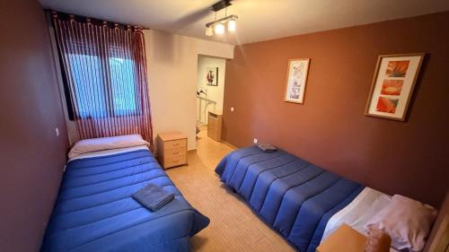 a bedroom with two beds and a blue couch at El Rincon De Los Abuelos in Tudela de Duero