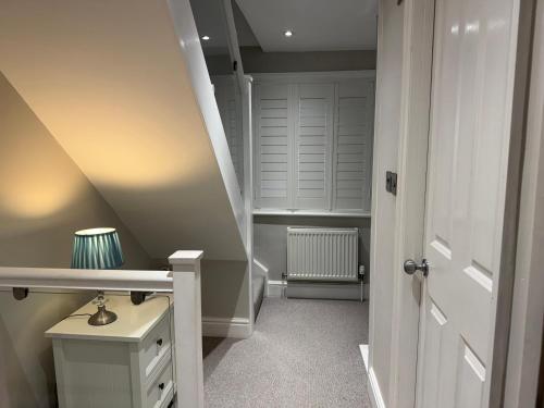 an attic hallway with a staircase and a white door at York Cottage in Southwold
