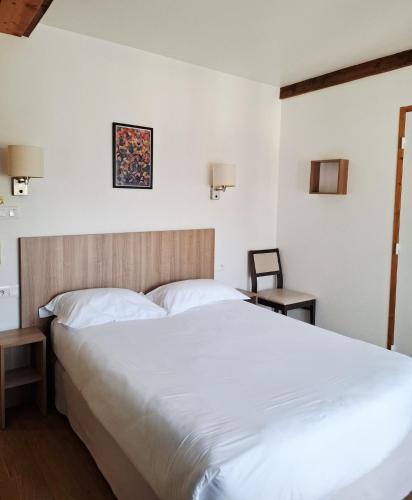 a bedroom with a large white bed and a chair at Le Grand Hôtel Ussel ''nouvelle Gérance 2023'' in Ussel