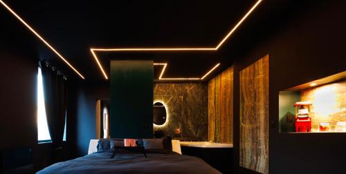 a bedroom with a bed and a bathroom with a sink at Suite Dark Luxe avec Écran géant de cinéma et jacuzzi in Clary