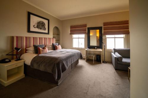 a bedroom with a bed and a couch and a chair at The Pier Hotel in Harwich