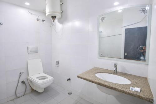 a white bathroom with a toilet and a sink at Mauryan Elite Hotel Vasant Kunj in New Delhi