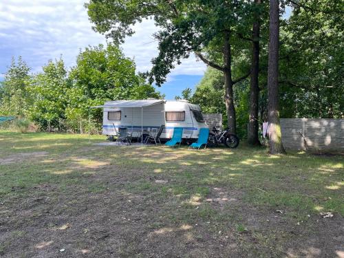 a trailer parked in a field next to a tree at Kemp Březák- Chlum u Třeboně in Golčŭv Jeníkov