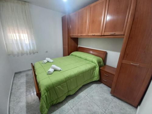 a small bedroom with a green bed and wooden cabinets at Casa O Capitán in Corcubión