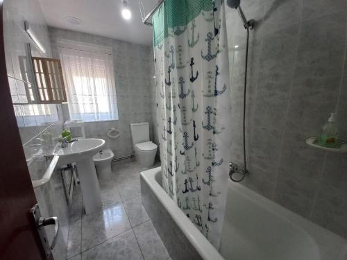 a bathroom with a tub and a sink and a toilet at Casa O Capitán in Corcubión