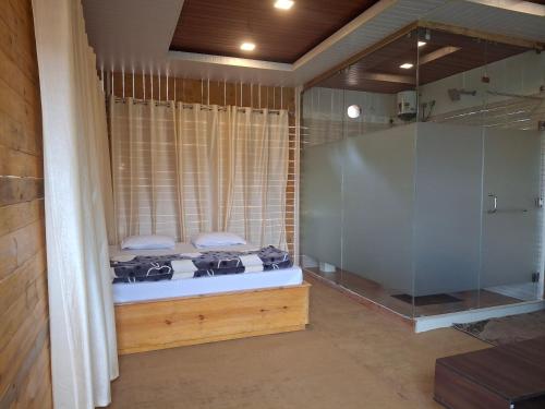 a bedroom with a shower and a bed and a tub at Ribhoi Jungle in Khānāpāra