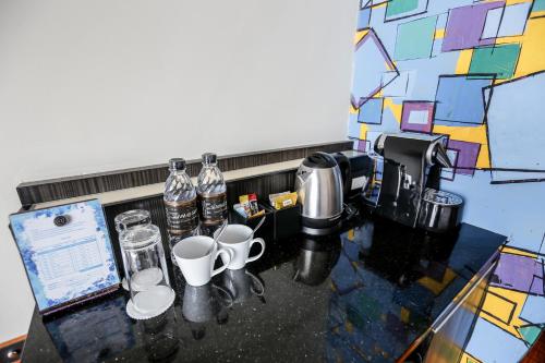 a counter with cups and bottles of water on it at Siam At Siam Design Hotel Pattaya in Pattaya