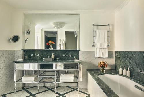 a bathroom with a tub and a large mirror at Rocco Forte The Carlton in Milan