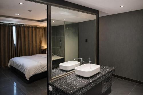a bathroom with a sink and a bed and a mirror at Zenith Tourist Hotel in Bucheon