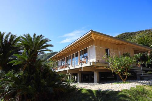 a house on the beach with palm trees in front of it at 泊まれるアートミュージアム 琉球ヴィラ in Tatsugo