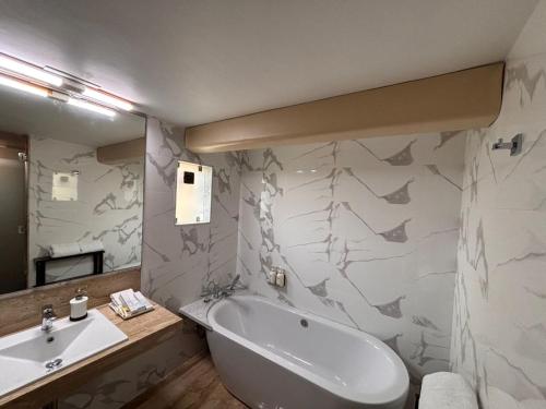a bathroom with a bath tub and a sink at Hiltop Hotel in Mumbai