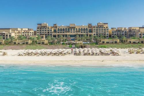 a beach with chairs and tables on the beach at Saadiyat Rotana Resort and Villas in Abu Dhabi