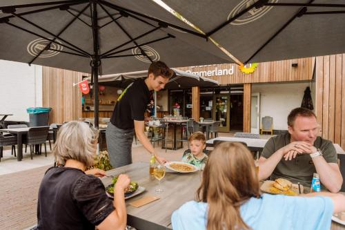 a group of people sitting around a table eating food at Vakantiepark Ommerland in Ommen