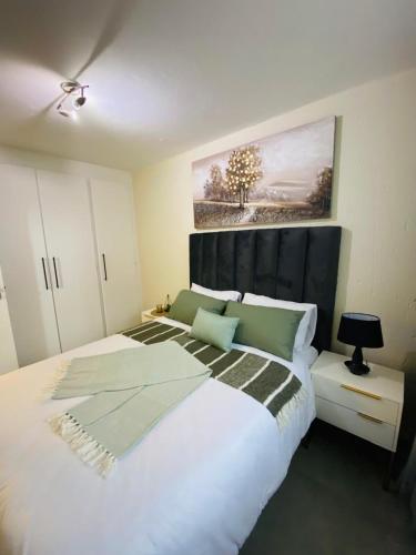 a bedroom with a large white bed with a black headboard at Villa Elizabeth - Fourways Gardens Sandton in Fourways
