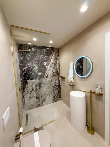 a bathroom with a shower and a toilet and a mirror at Vatër Selected Rooms in Tirana