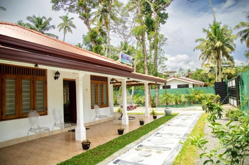 a home with a patio with chairs and trees at Villa Hatange in Weligama