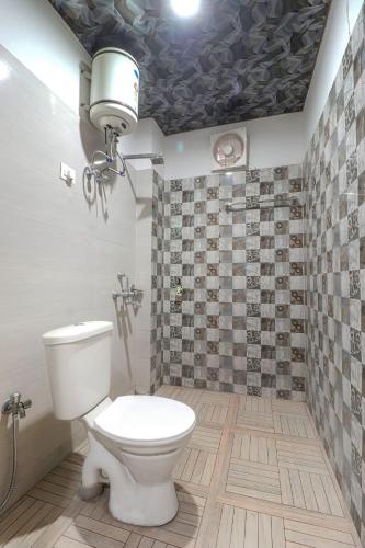 a bathroom with a toilet and a tiled wall at Hotel Kanha in Haridwār