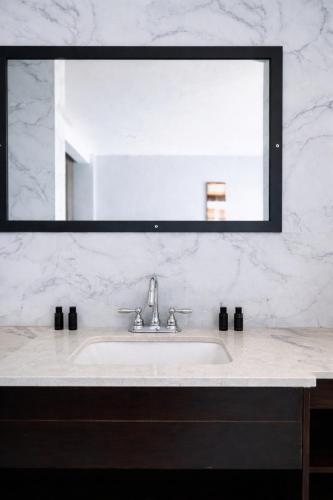 a bathroom sink with a large mirror above it at Tris Estates Hotel & Suites in Dwarzohn