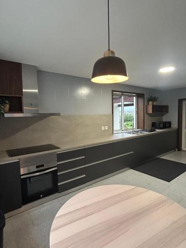 a large kitchen with a pendant light and a table at Barcelos Residence Living in Barcelos
