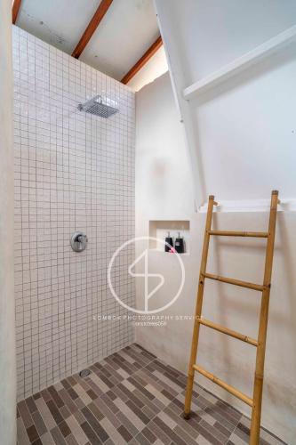 a ladder in a bathroom with white tiles at Ings Garden Acommodation in Gili Islands