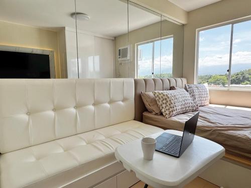 a living room with a white couch and a laptop on a table at Bears Nook - Marina Spatial Dumaguete in Piapi