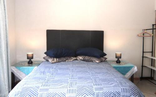 a bedroom with a bed with a black headboard and two lamps at Rosy Palm Sunrise in Upington