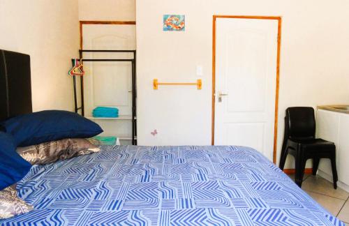 a bedroom with a blue and white bed with a chair at Rosy Palm Sunrise in Upington