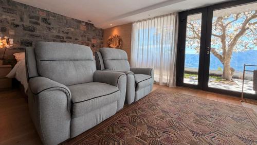a living room with two chairs and a large window at ROMANTIC SUlTE WITH ITS OWN SPA AND OPEN VIEW TO LUGANO in Cademario