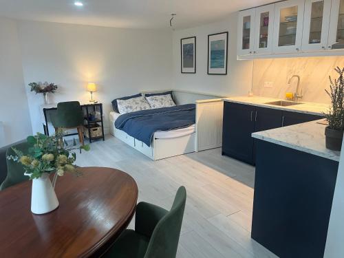 a room with a bed and a table and a kitchen at Wisteria en-suite guest room in Hillingdon