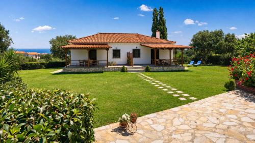 a small white house with a grass yard at Dora Apartments in Tragaki