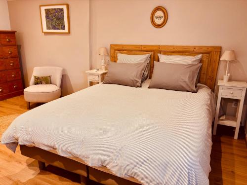 a bedroom with a large white bed and a chair at La Bastide des Dentelles in Roaix