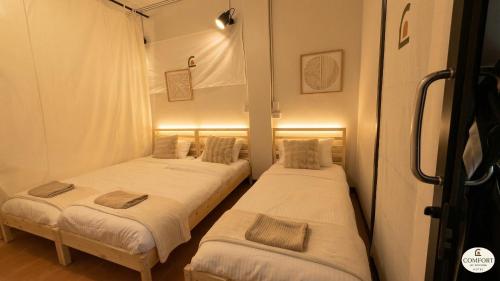 two beds in a room with white sheets at Hostel Bangkok Airport Comfort By MaTong " Near Suvarnabhumi Airport BKK " in Suvarnabhumi Airport