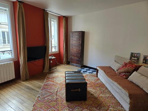 a living room with a couch and a tv at La Grande Glycine in Coulommiers