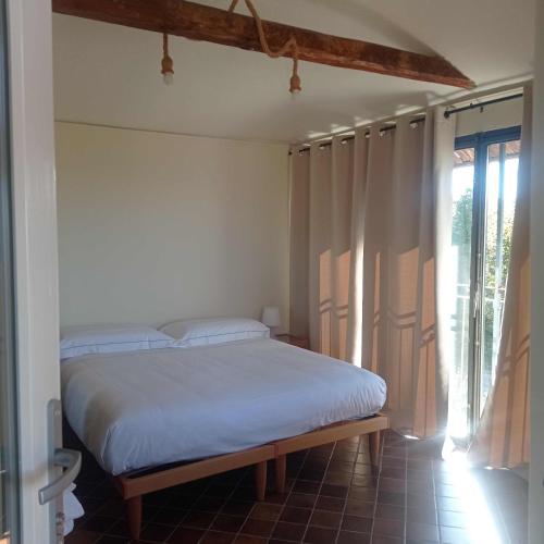 a bedroom with a bed with white sheets and a window at Agriturismo Cascina Binelli in Dogliani