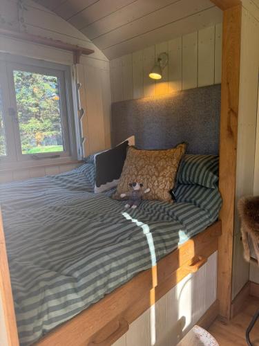 a bed in a tiny house with a window at Chez Marguerite Luxury Shepherd's Hut and Sauna in Holt
