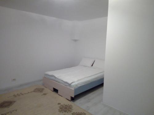 uma pequena cama num quarto com uma parede branca em Reben Haus em Sibiu