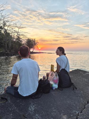 a man and woman sitting next to the water watching the sunset at King seafood koh kood in Ban Khlong Mat