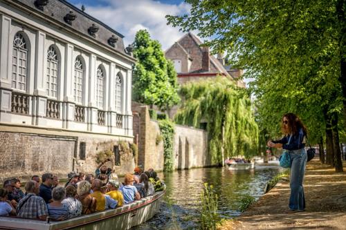 a group of people riding in a boat on a river at Golden Tulip Hotel de’ Medici in Bruges