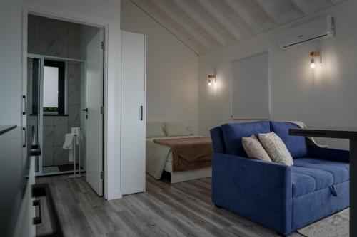 a living room with a blue couch and a bedroom at AL Adega do Calcetas in Cais do Mourato