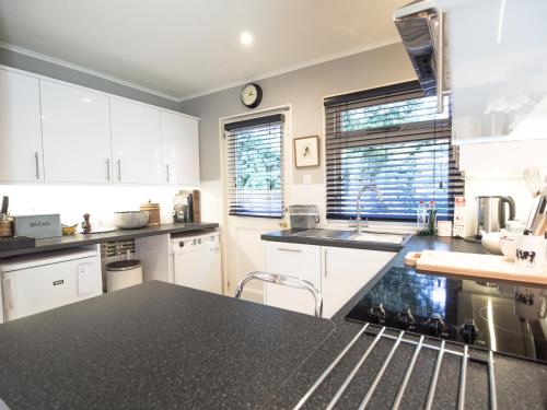 eine Küche mit weißen Schränken und einer schwarzen Arbeitsplatte in der Unterkunft Yew Tree Cottage in Maidford