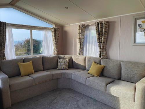 a living room with a large couch with yellow pillows at Hendre Coed Isaf Caravan Park in Barmouth