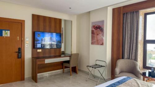 a hotel room with a bed and a desk with a tv at Corp Yanbu Hotel - B2 in Yanbu