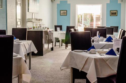 a dining room with tables and chairs with white table cloth at The Avenue in Shanklin