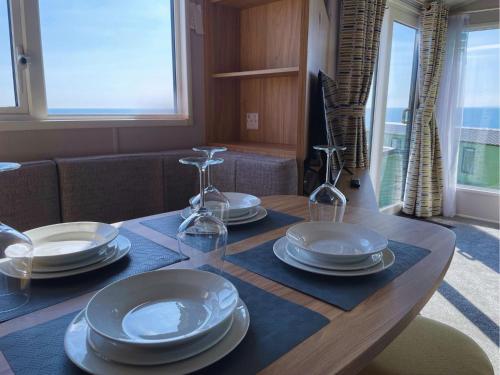 a dining room table with plates and glasses on it at Hendre Coed Isaf Caravan Park in Barmouth