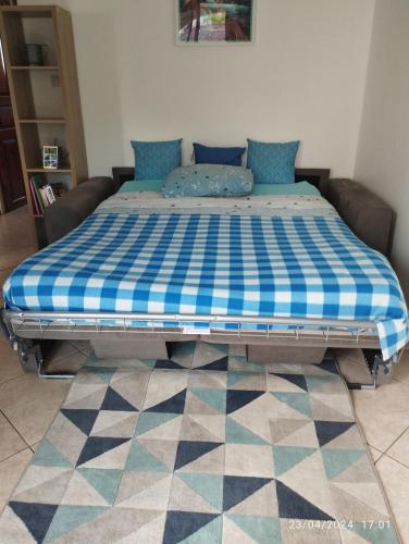 a bed with a blue and white checkered mattress at Appartement 974 in Le Tampon