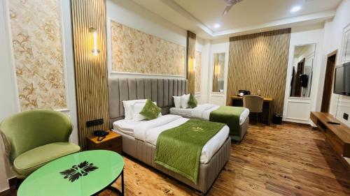a hotel room with two beds and a green chair at Red Leaf Hisar in Hisār